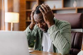 Premium Photo | Sad frustrated adult african american guy in casual hold  his head with hand watch at laptop suffer from stress